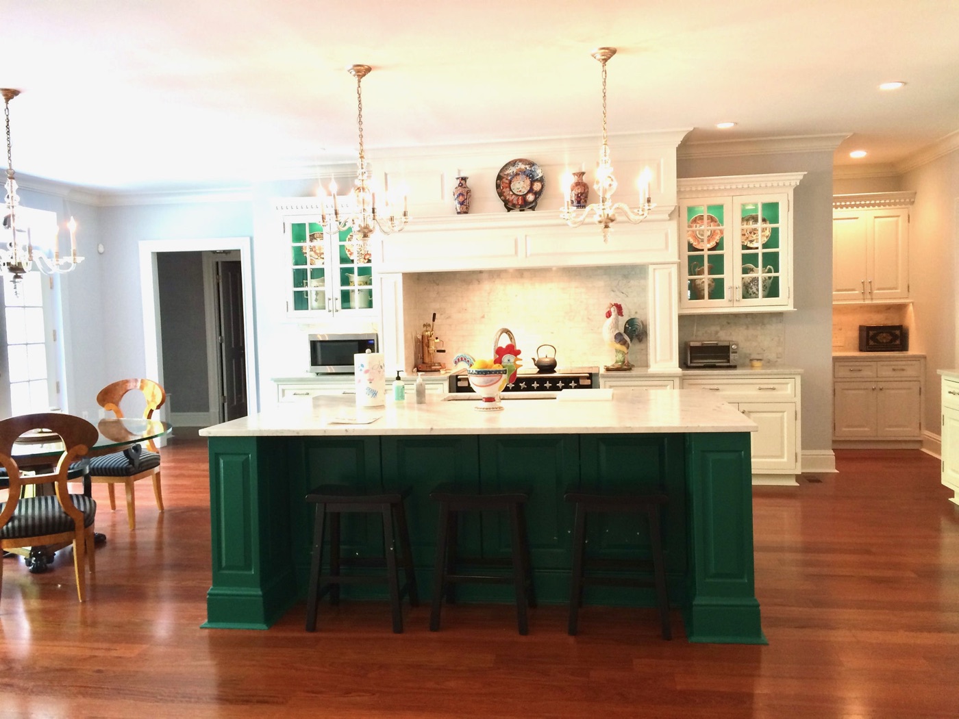 Open-concept kitchen with green island, marble countertops, and organized cabinetry