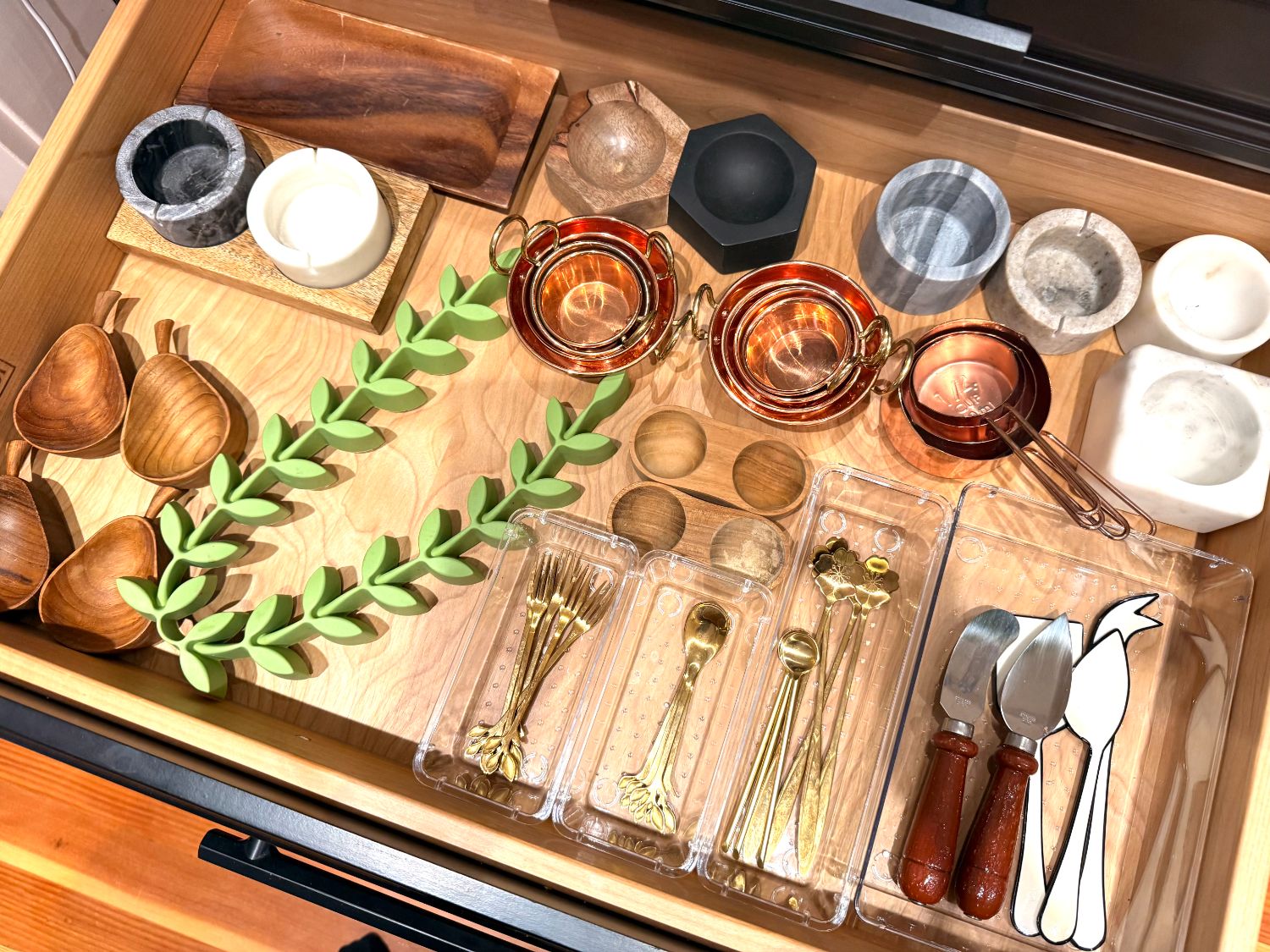 A kitchen serving drawer organized with copper and marble accents
