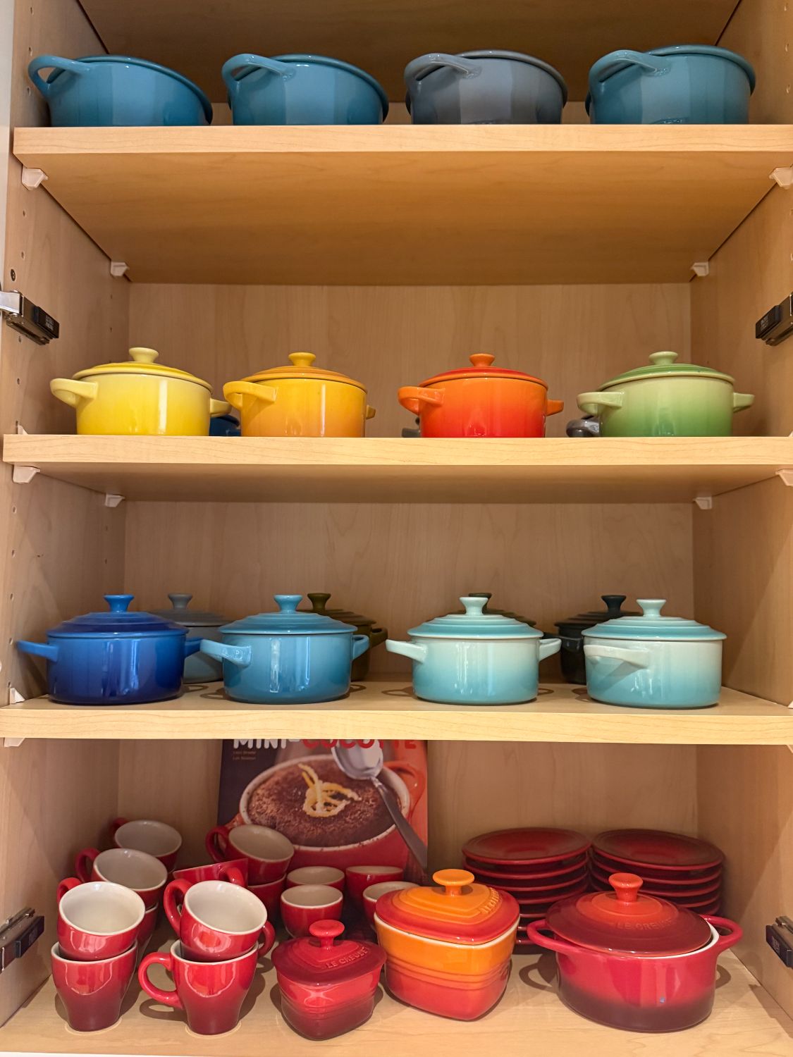 A rainbow of Le Creuset cookware, neatly arranged